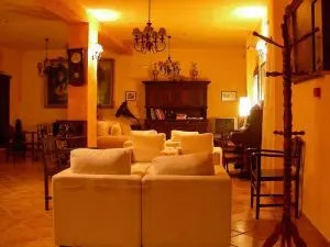 Salón con varios sillones muy cómodos, cuadros antiguos, aparadores de estilo señorial, y un piano antiguo.